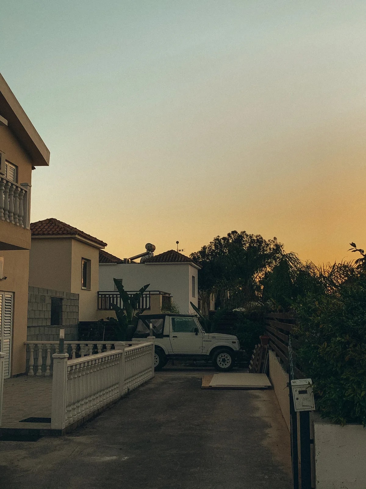 Beige townhouses behind low white walls and palms at sunset, like the Al Raha Gardens townhouses we automate