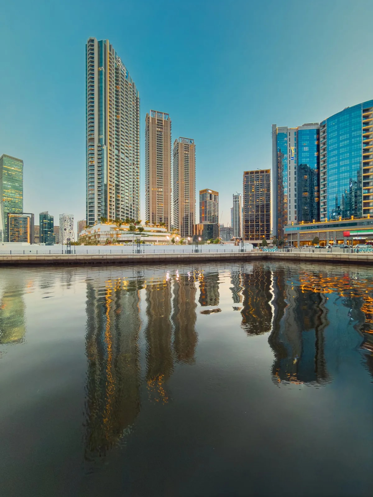 Business Bay towers reflected in the Dubai Water Canal at dusk, where we design smart homes