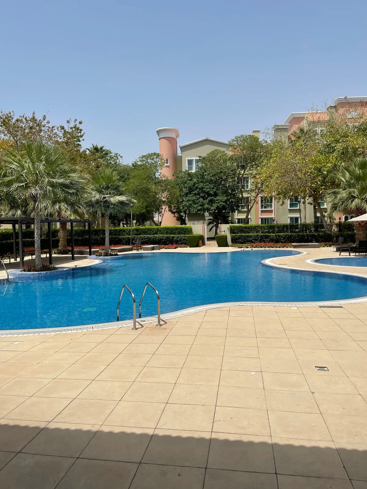Shared pool and palms by low-rise flats, like the Jumeirah Village Circle homes we automate