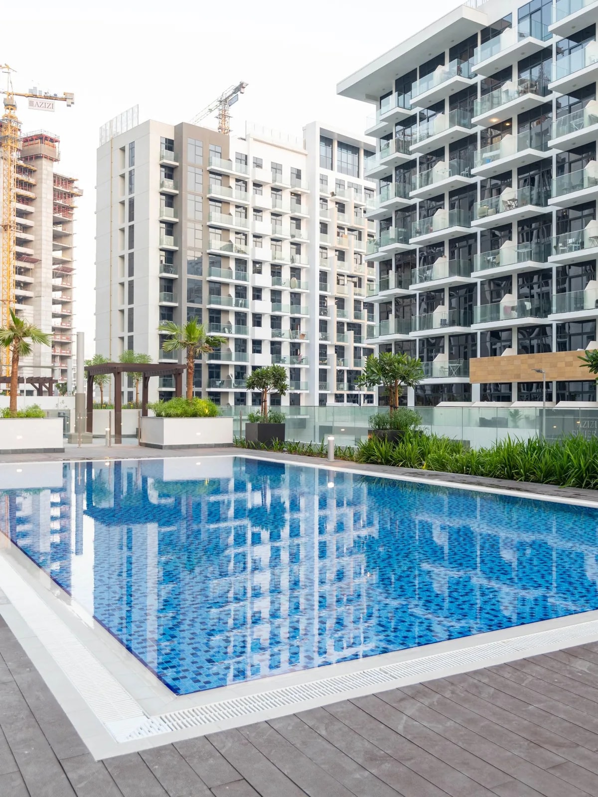 Blue pool on a paved deck below balconied flats, like the Sobha Hartland apartments we automate