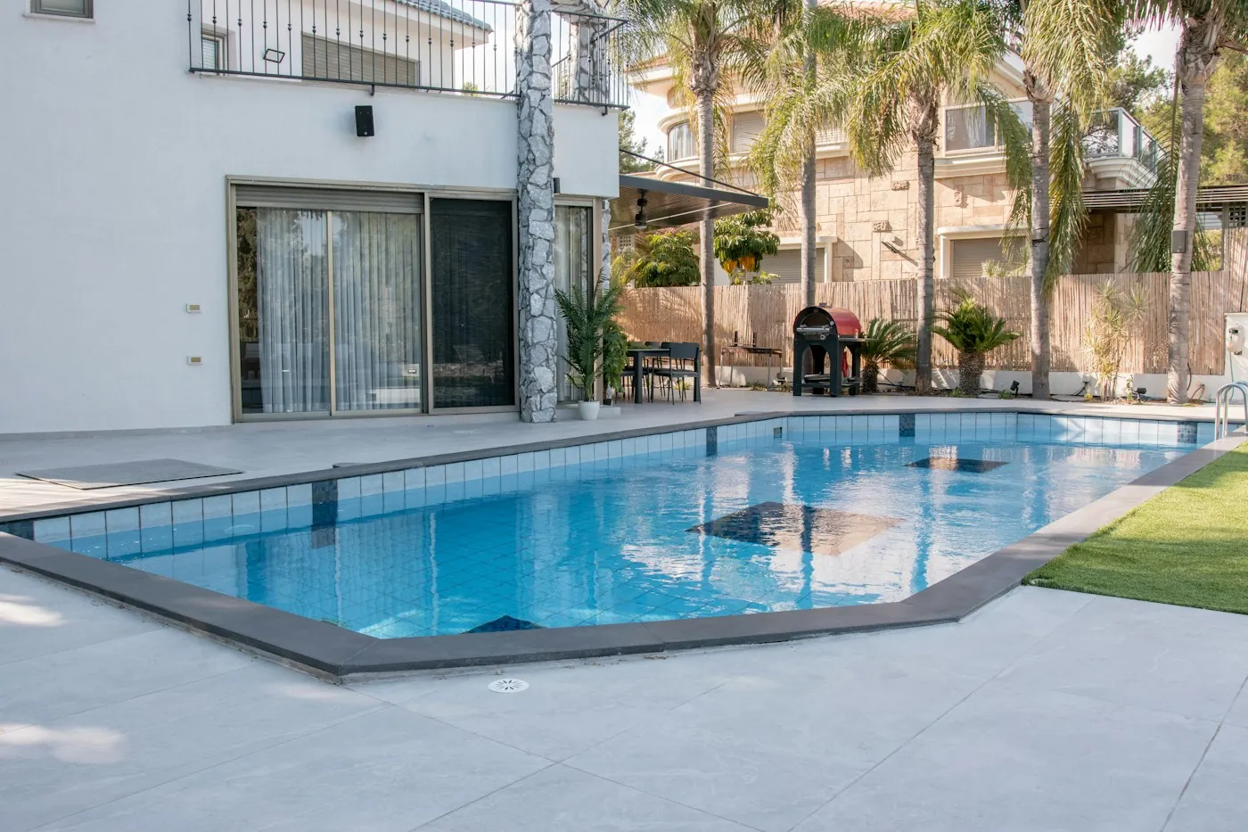 Modern villa swimming pool and garden terrace with palm trees