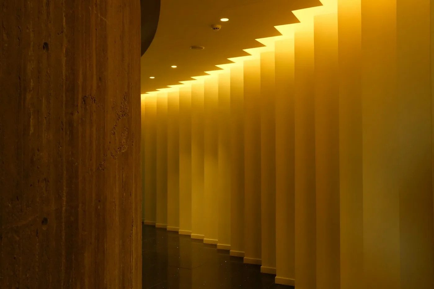 Modern corridor lit by a warm amber cove lighting strip along the ceiling