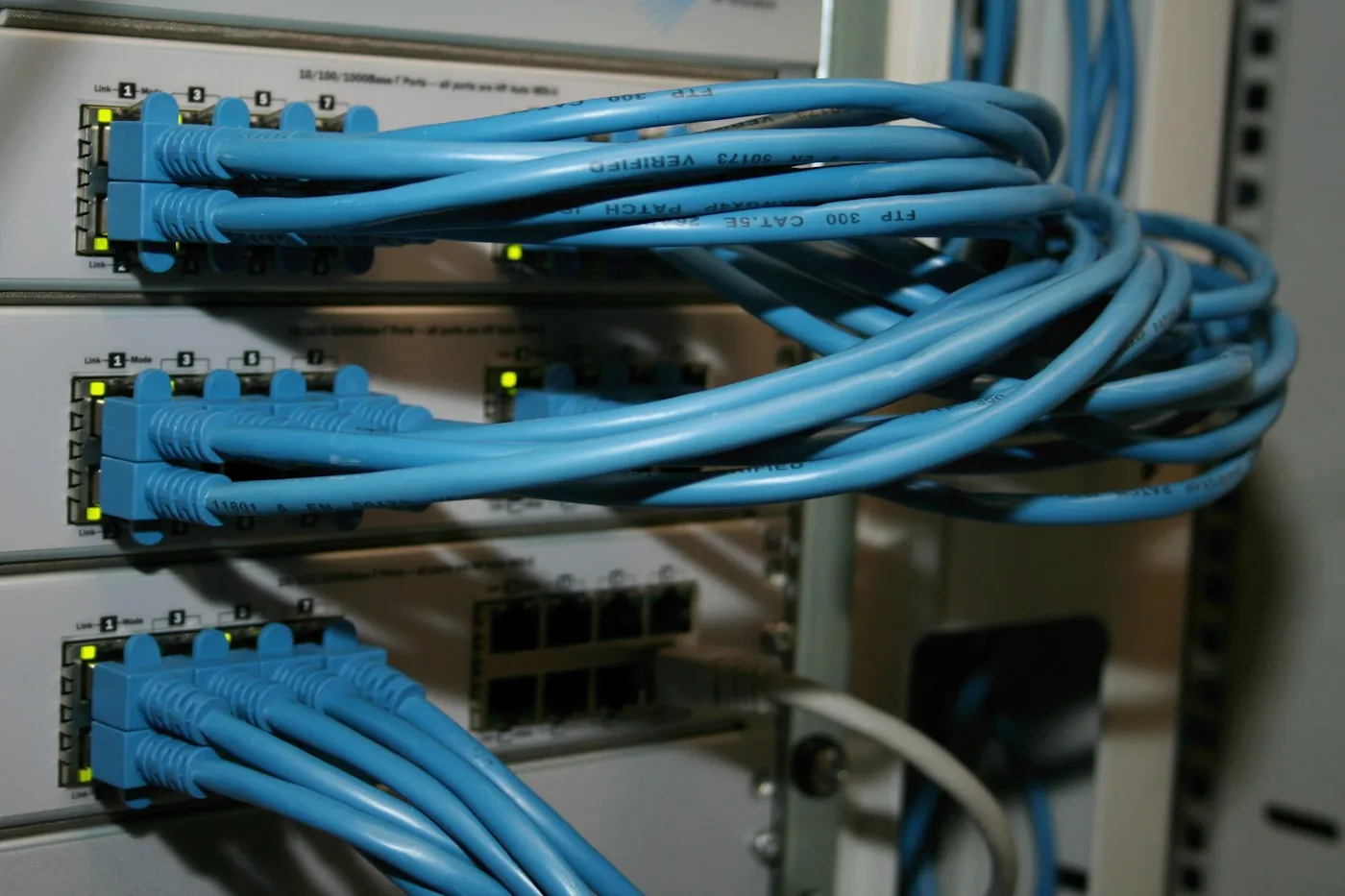 Blue patch cables neatly connected into a structured cabling patch panel in a network rack