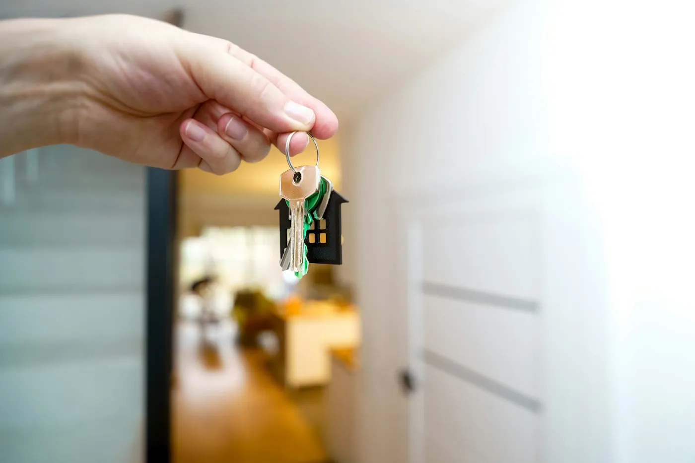 Hand holding house keys at the entrance of a newly handed over home