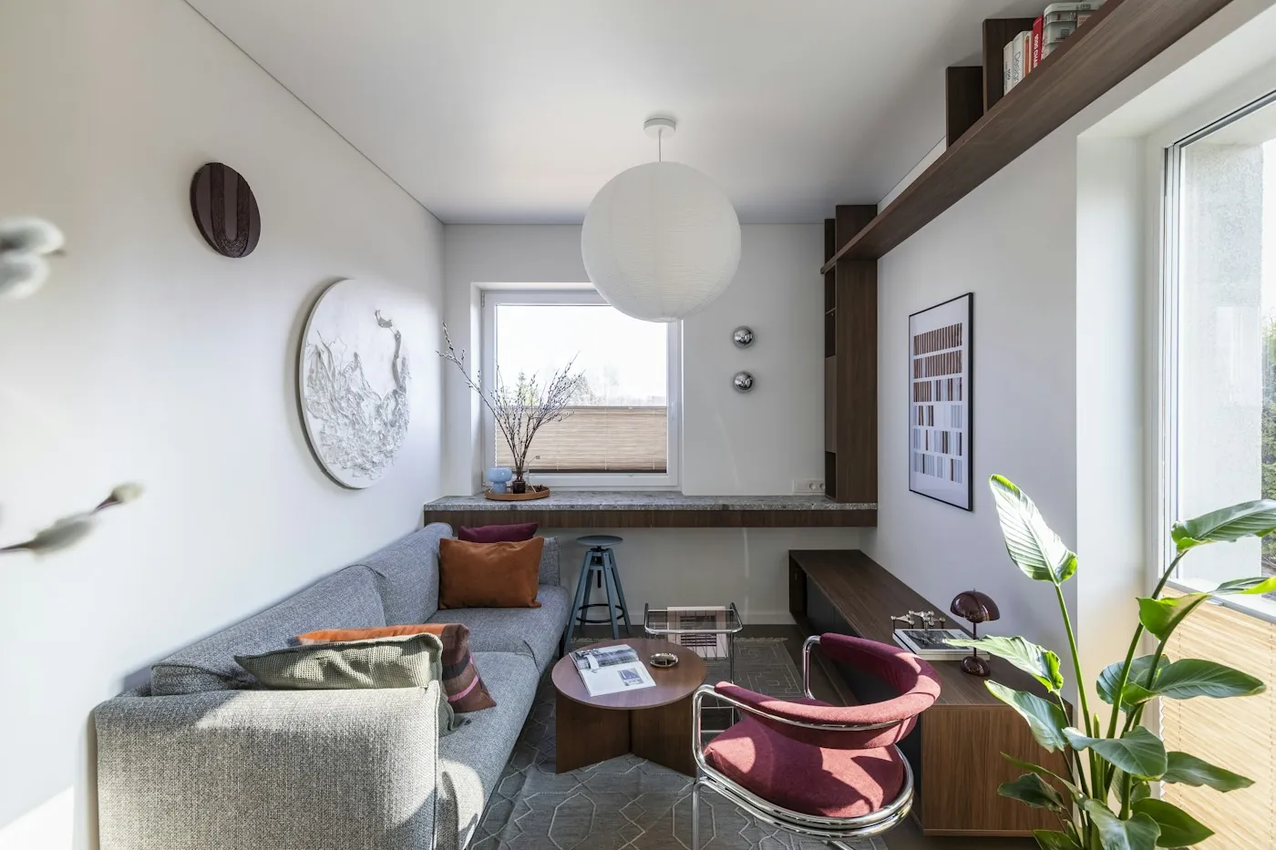 Bright apartment living room with a grey sofa, large window and shelving