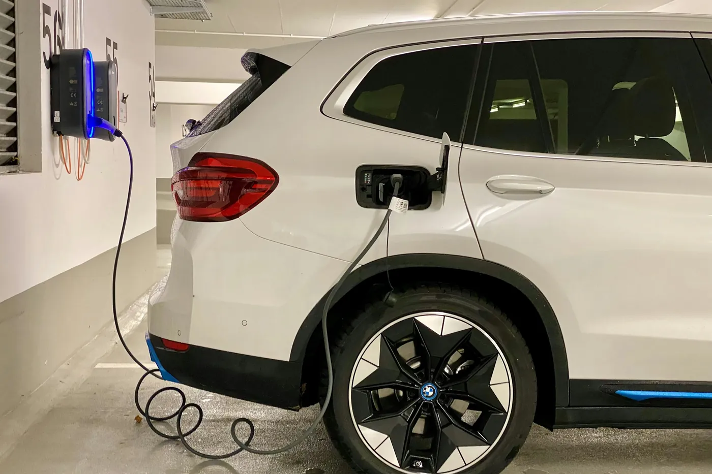Electric car plugged into a wall-mounted home EV charger in a garage