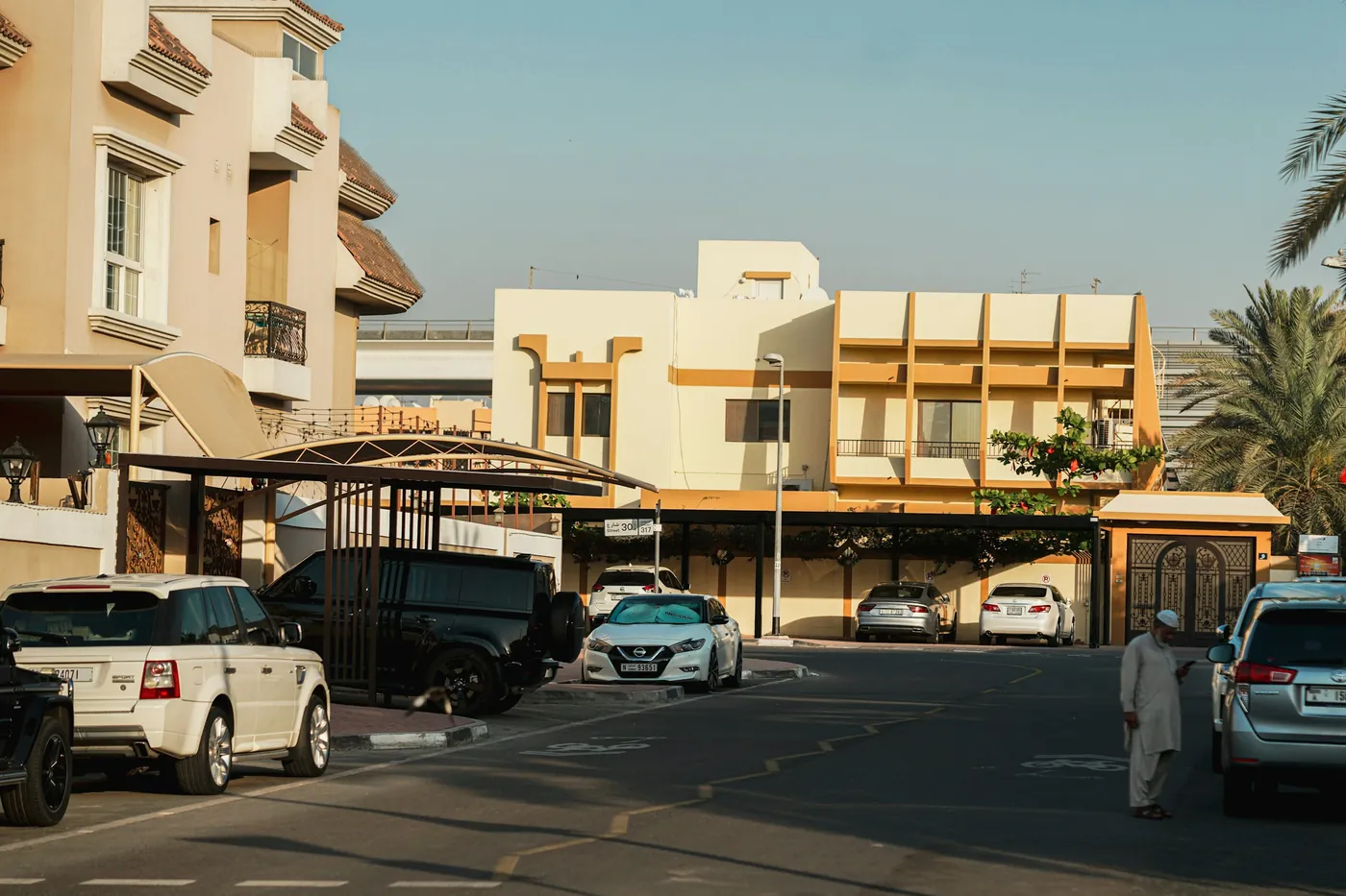 Cars parked in full sun on a villa community street, the same heat an outdoor EV charger faces