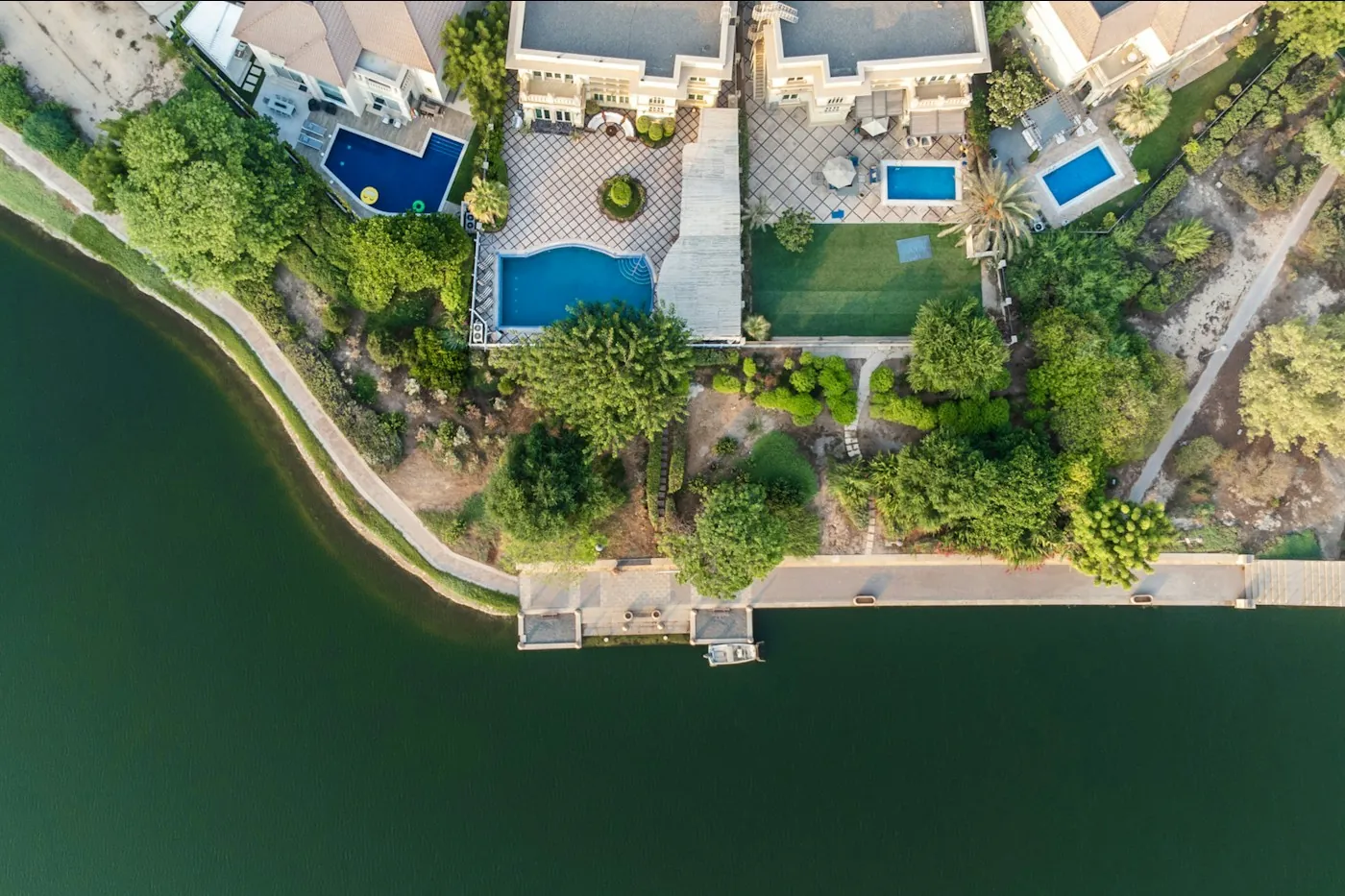 Aerial view of lakeside villas with private pools in a Dubai community
