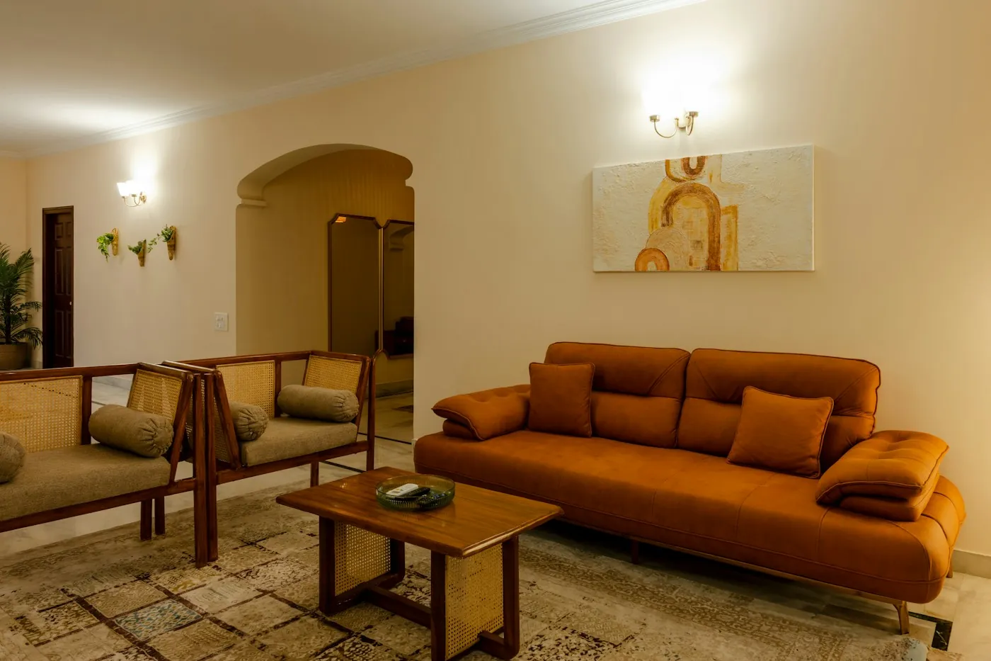 Elegant arched-doorway villa living room with a warm orange sofa and designer lighting