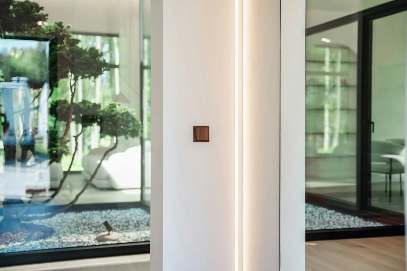 Small wall-mounted smart home keypad beside floor-to-ceiling glass in a modern villa hallway