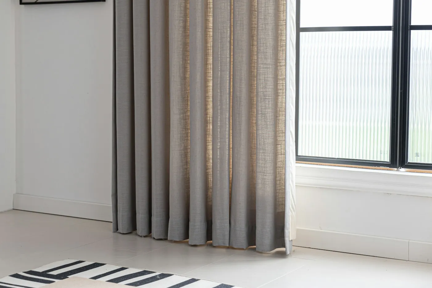 Heavy grey curtains fully drawn across a large window in a bright modern room