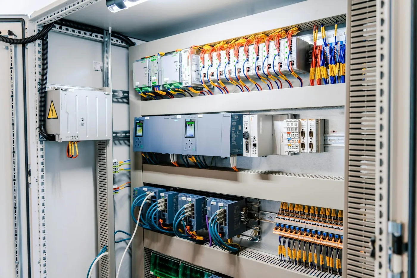 Open electrical control cabinet with DIN rail modules and bundled wiring