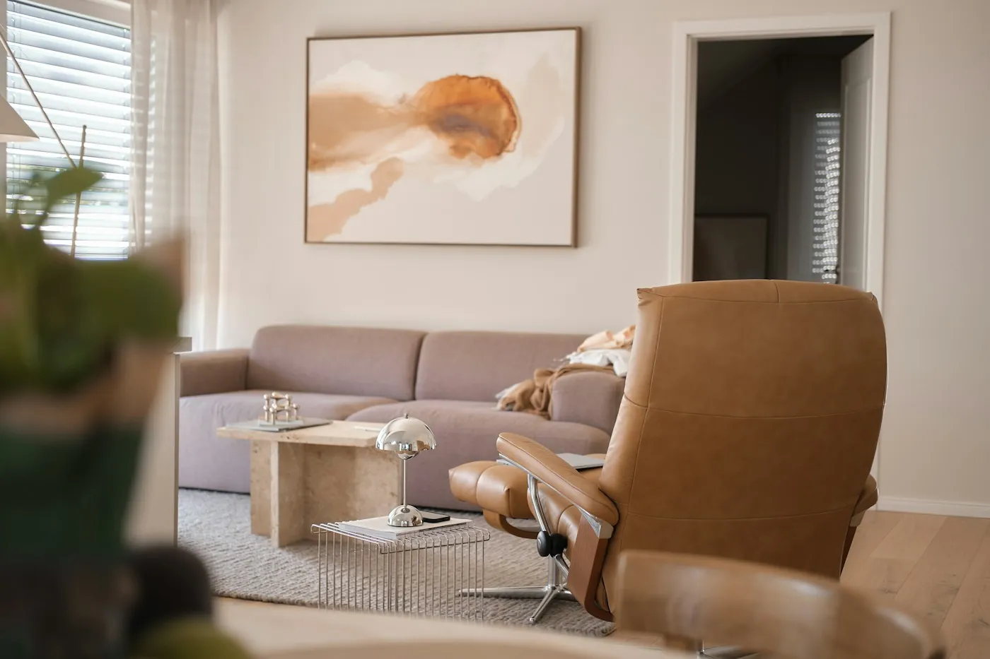 Sunlit living room with a comfortable tan leather recliner and a soft sofa