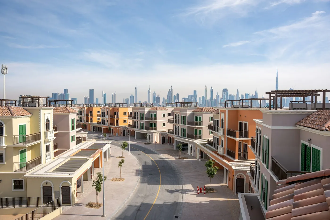 Colourful townhouse row in a Dubai community with the city skyline behind