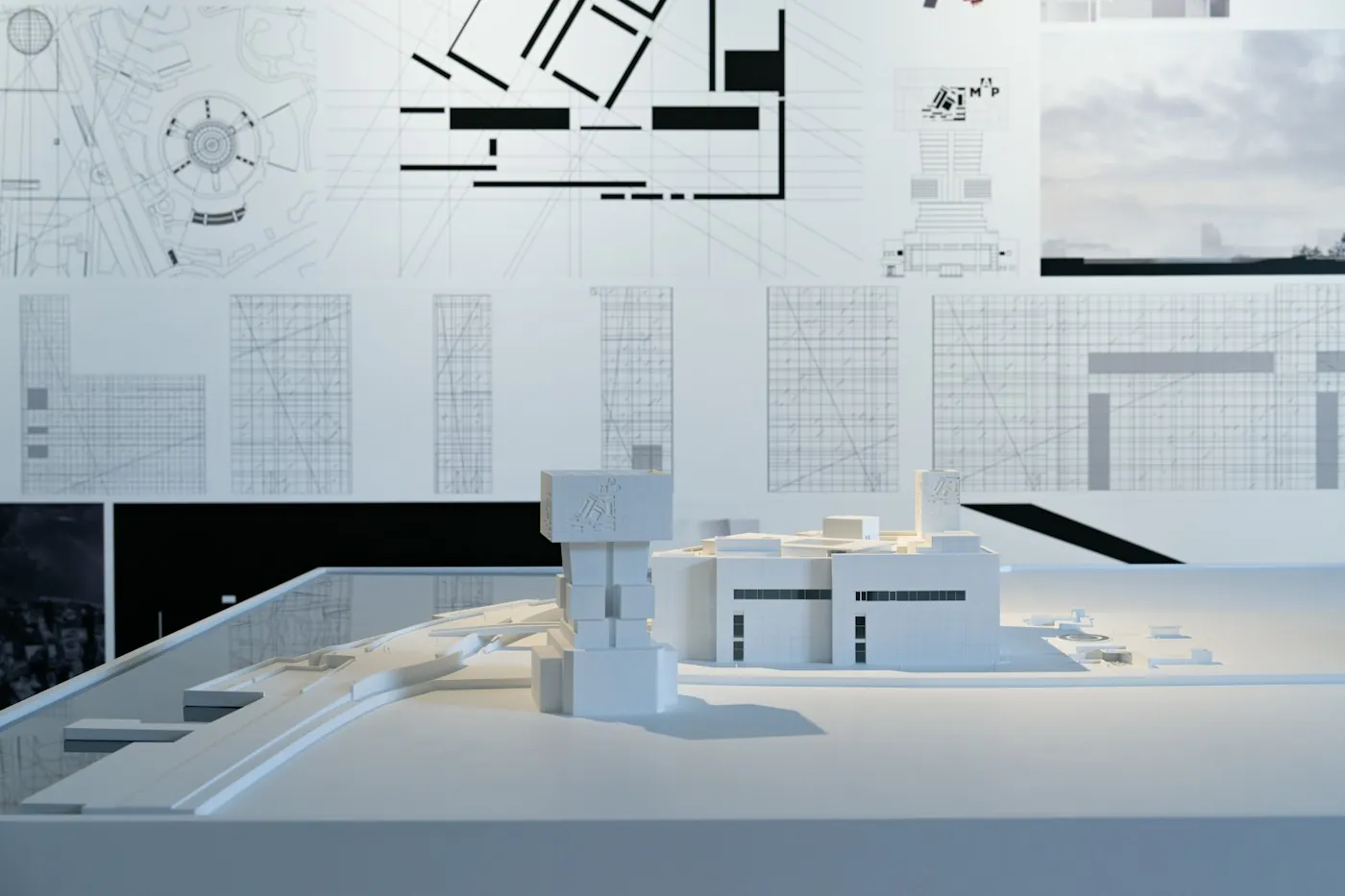 Architectural model of a house next to blueprints pinned on a wall