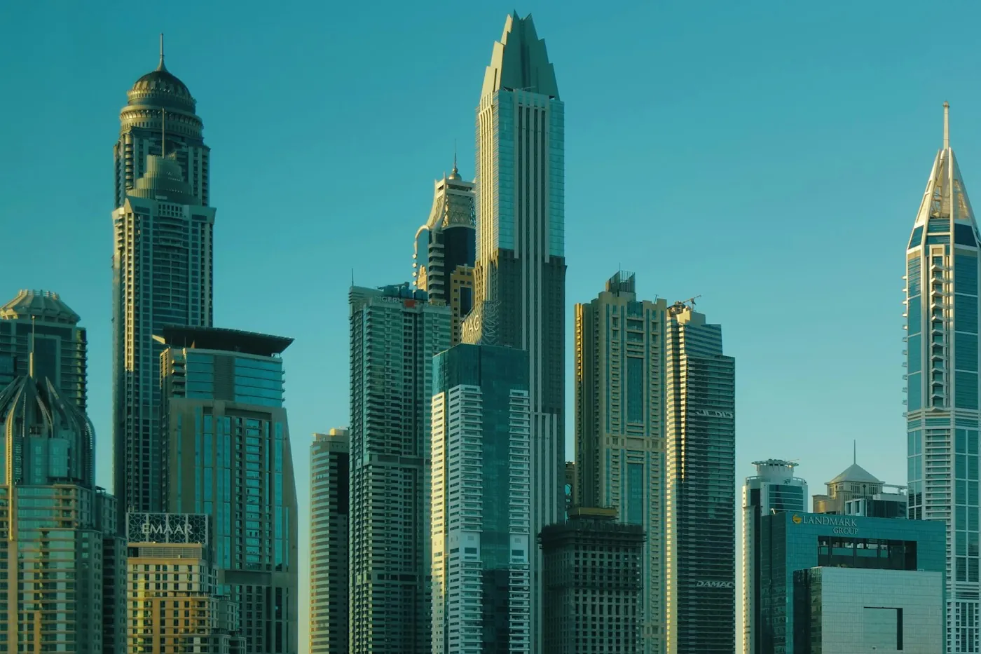 A cluster of Dubai high rise towers at golden hour, the kind of dense apartment buildings typically served by a district cooling plant