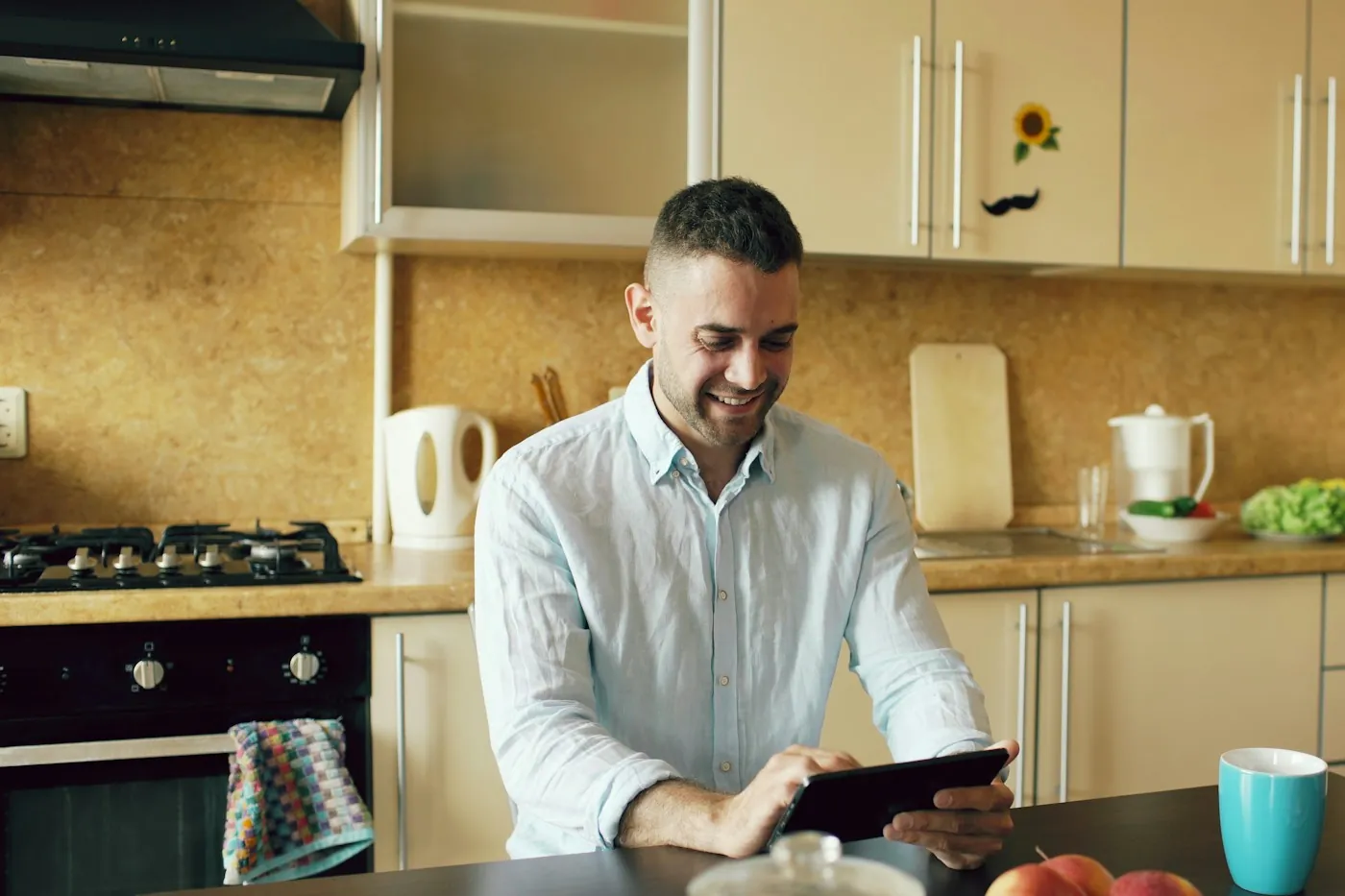 A man using a tablet at a kitchen counter in an apartment