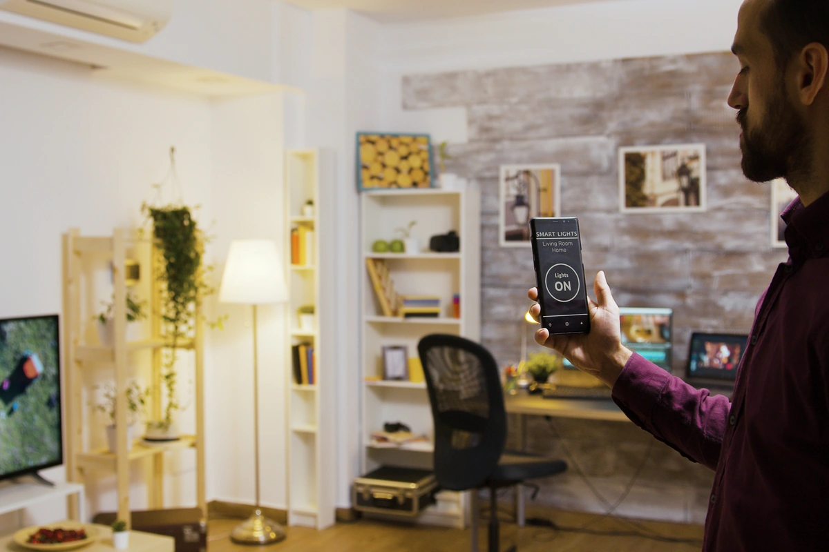 Man controlling smart lights from a phone app in a Dubai apartment, representing DIY voice control